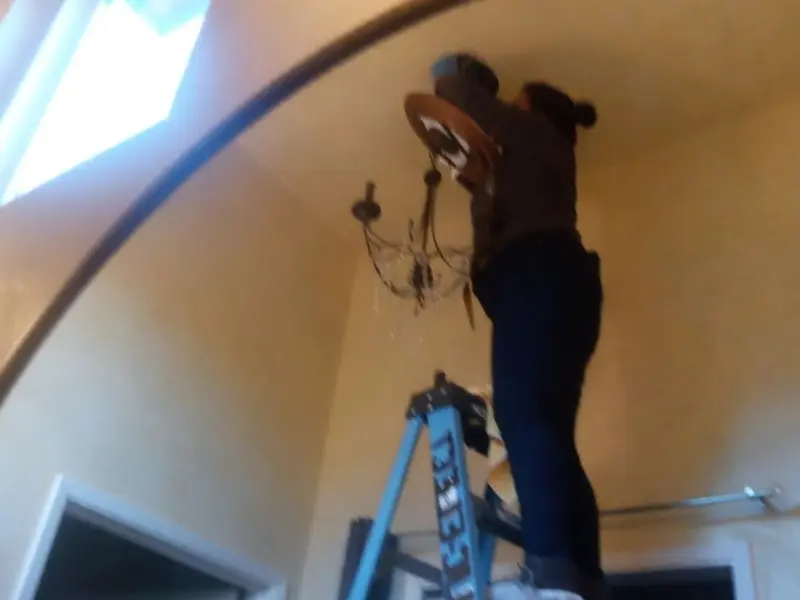 Electrician installing a chandelier in a Coal residence
